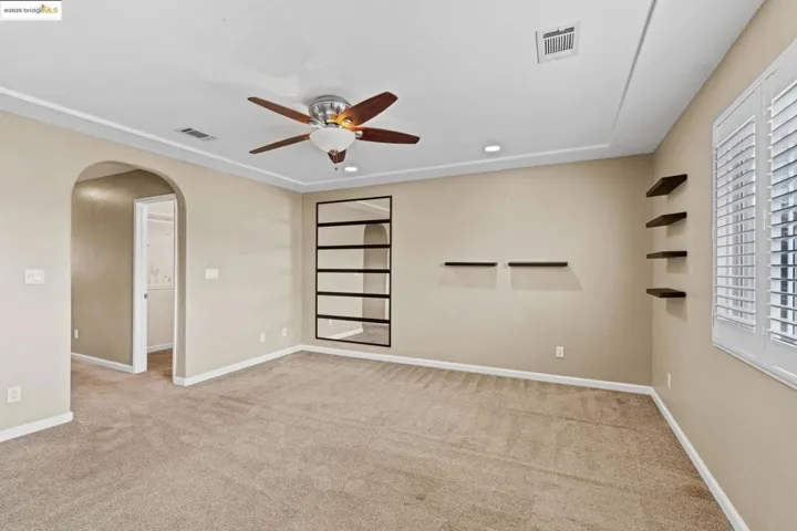 Carpeted spare room with arched walkways, a ceiling fan, and recessed lighting