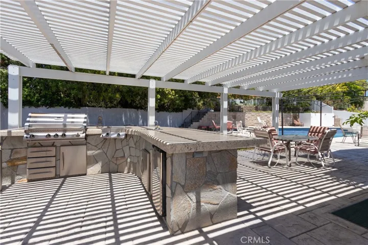 Outdoor kitchen with BBQ, grill, fridge, and sink with hot & cold water