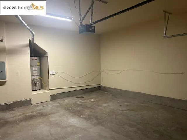 Garage with strapped water heater and a garage door opener