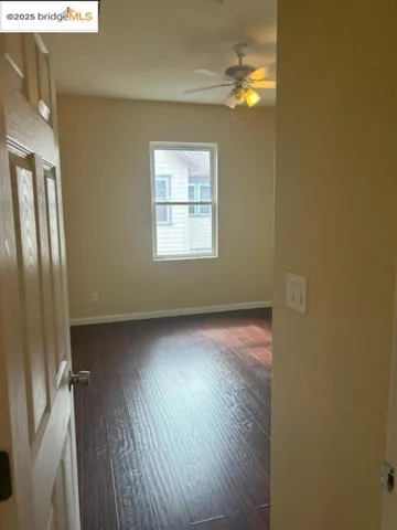 Spare room featuring dark wood finished floors and a ceiling fan