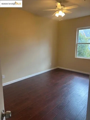 Spare room with a ceiling fan and dark wood-style floors
