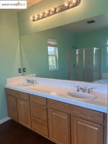 Full bathroom with a shower stall, wood finished floors, and double vanity
