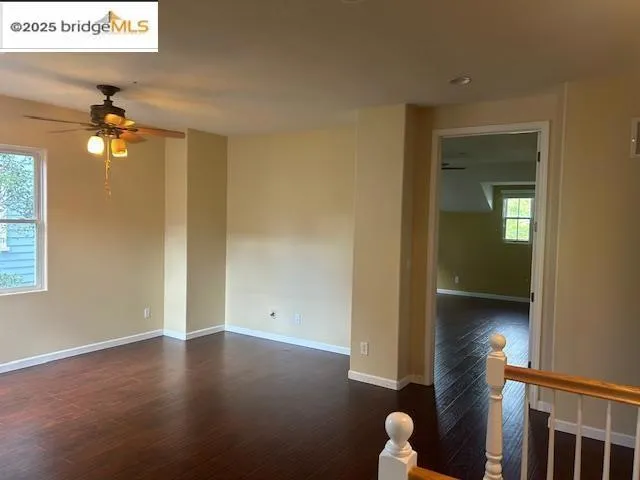 Spare room with dark wood-style floors and a ceiling fan