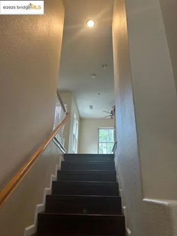 Stairs with a textured wall and ceiling fan