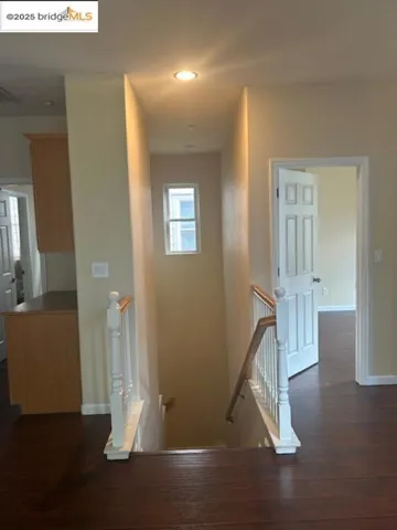 Hall with an upstairs landing, dark wood-style floors, and recessed lighting