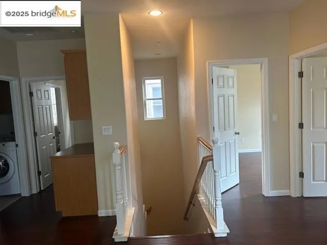 Corridor featuring an upstairs landing, washer / dryer, dark wood-type flooring, and recessed lighting