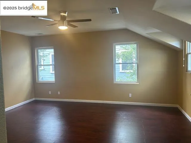 Additional living space with plenty of natural light, ceiling fan, dark wood finished floors, and vaulted ceiling