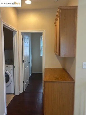 Corridor featuring dark wood-style flooring and washer / dryer