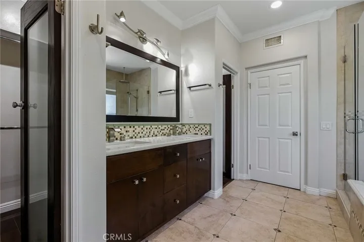 There are 2 entrances with custom glass doors to this walk through closet ready with built-ins for all your needs including a custom shoe rack.
