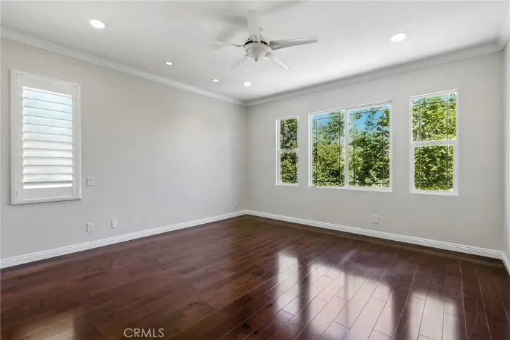 Huge primary bedroom with view of trees and park. Custom lighting and ceiling fan.