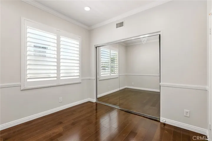 A sizable upstairs bedroom with mirrored wardrobe closet doors and shutters.