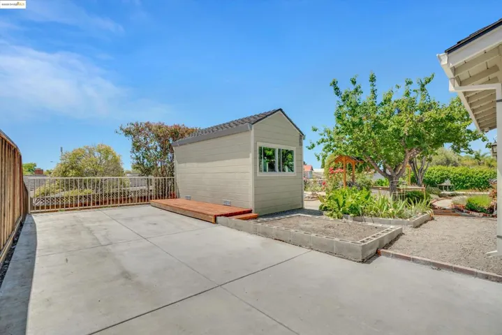View of patio with a vegetable garden and a storage shed