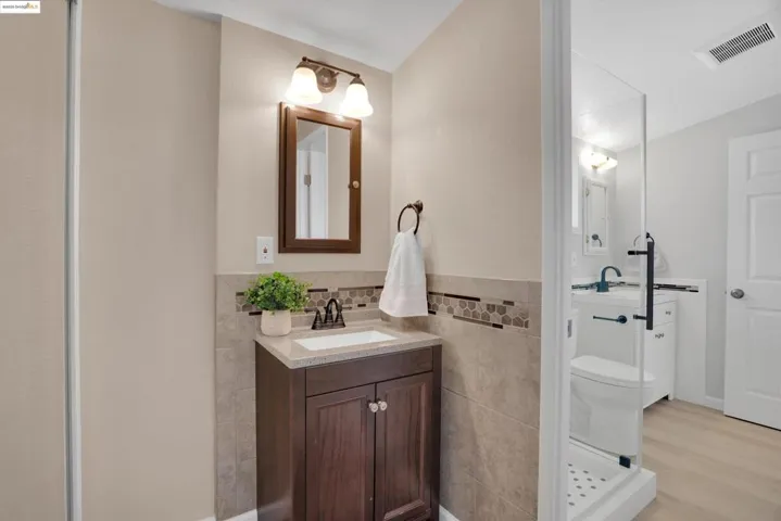 Full bathroom featuring tile walls, vanity, and wood finished floors