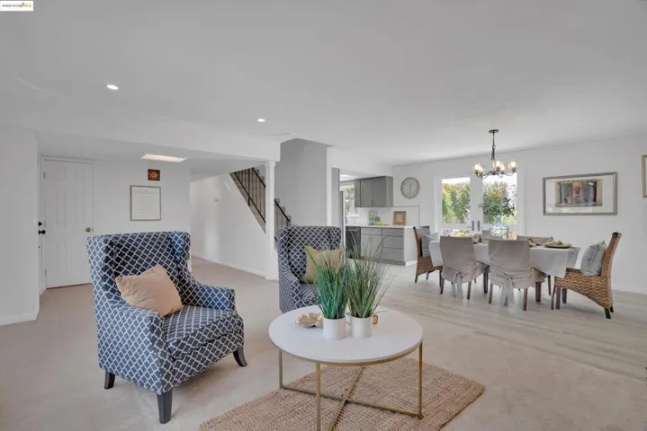 Living room with stairway, a chandelier, recessed lighting, and light carpet