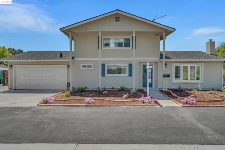 View of front of home with an attached garage, concrete driveway, a chimney, stucco siding, and roof with shingles