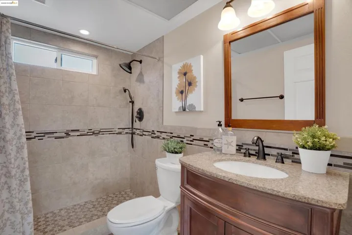Bathroom featuring vanity, tiled shower, recessed lighting, and tile walls