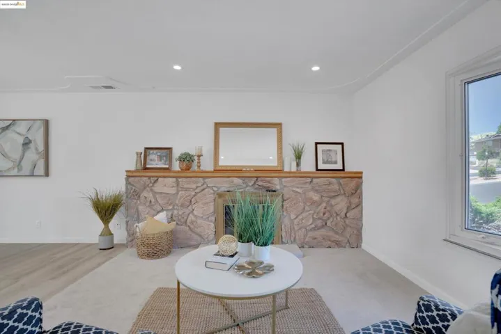 Living room with a stone fireplace, plenty of natural light, and recessed lighting