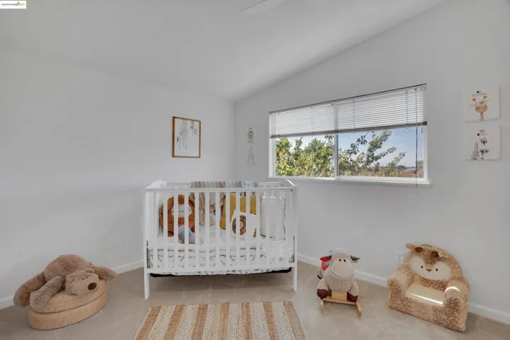 Carpeted bedroom with lofted ceiling and a crib