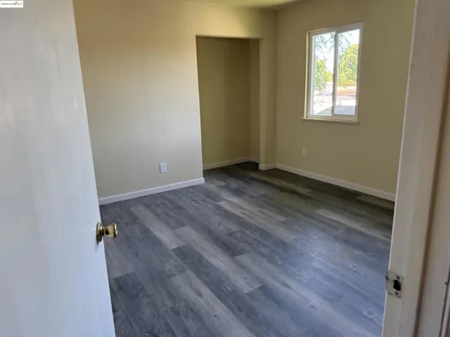 Spare room featuring baseboards and dark wood finished floors