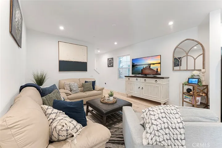 Living room with high ceilings, recessed lighting, LVP flooring. You can add a ceiling fan if desired.