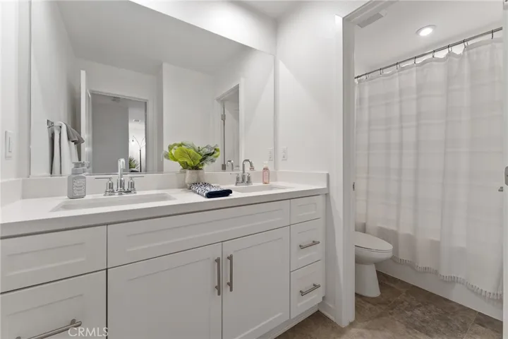 Upstairs full bath with dual sink and privacy door for the commode and shower in tub.