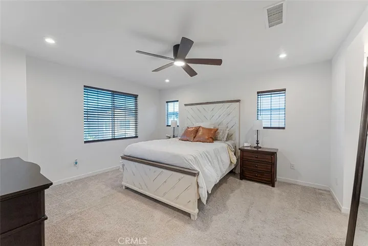 Spacious primary bedroom with recessed lighting, ceiling fan and en suite to the right.