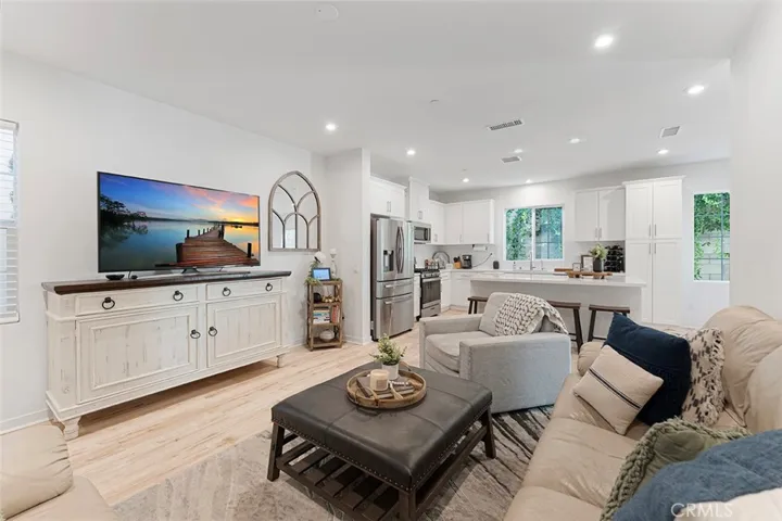 Living room with high ceilings, recessed lighting, LVP flooring. You can add a ceiling fan if desired.