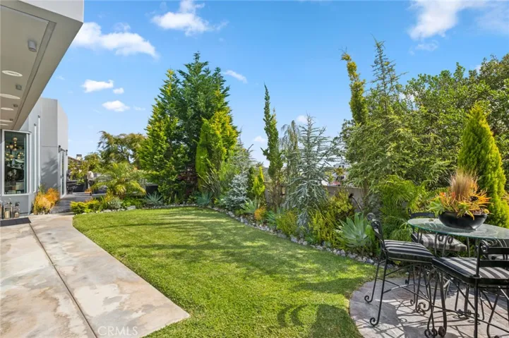 The outdoor living space is truly exceptional, featuring a built-in BBQ, fire pit, tranquil water feature, lush lawn, and multiple seating areas—perfect for entertaining or simply relaxing in your own private oasis