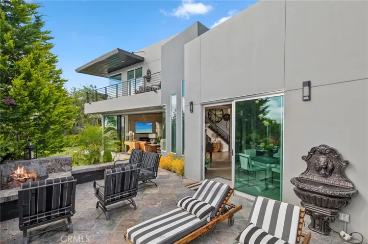 The outdoor living space is truly exceptional, featuring a built-in BBQ, fire pit, tranquil water feature, lush lawn, and multiple seating areas—perfect for entertaining or simply relaxing in your own private oasis