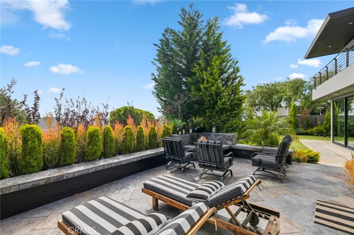 The outdoor living space is truly exceptional, featuring a built-in BBQ, fire pit, tranquil water feature, lush lawn, and multiple seating areas—perfect for entertaining or simply relaxing in your own private oasis