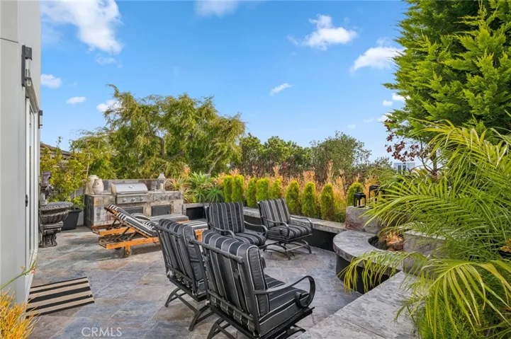 The outdoor living space is truly exceptional, featuring a built-in BBQ, fire pit, tranquil water feature, lush lawn, and multiple seating areas—perfect for entertaining or simply relaxing in your own private oasis
