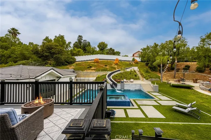 AMAZING BACKYARD..... THIS VEIW FROM THE PRIMARY BEDROOM DECK TO THE BACKYARD POOL WITH 75 FT. SLIDE, PERMITTED GUEST HOUSE, CURRENTLY BEING USED AS A POOL HOUSE, UPPER RIGHT CORNER OF PROPERTY IS A LARGE GATED R/V PARKING ACCESSED FROM STREET BEHIND.