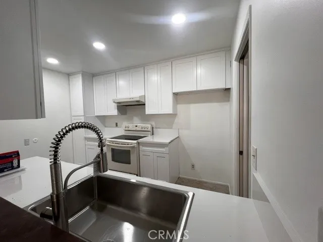 Newly updated kitchen with recessed lighting, sink and cabinets.