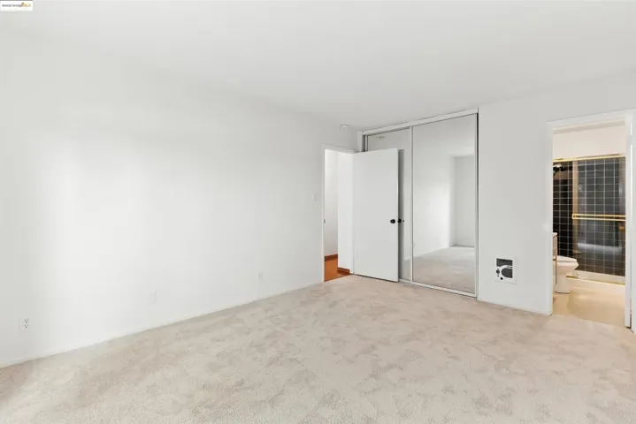 Unfurnished bedroom featuring carpet floors, ensuite bathroom, and a closet