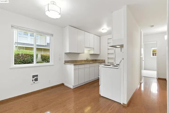Kitchen with plenty of natural light, light wood-type flooring, white electric range oven, and white cabinetry