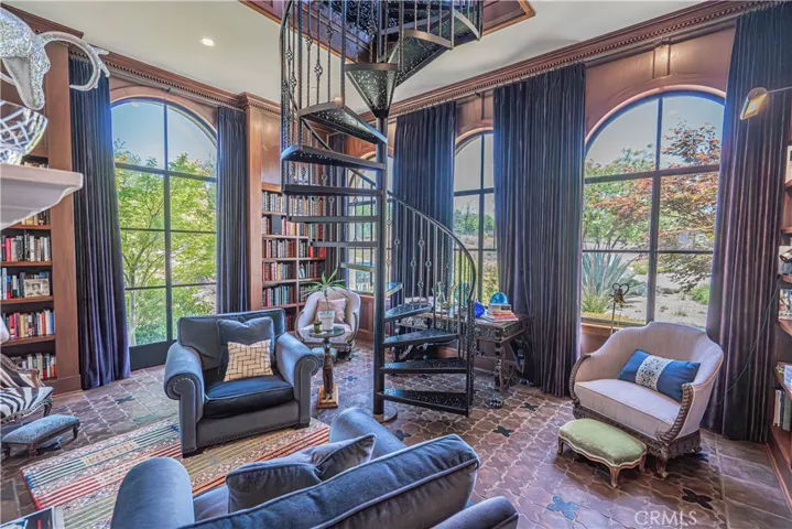 The downstairs library is filled with natural light and features a captivating spiral staircase that leads to an upper-level library seating area — perfect for quiet reading or reflection.