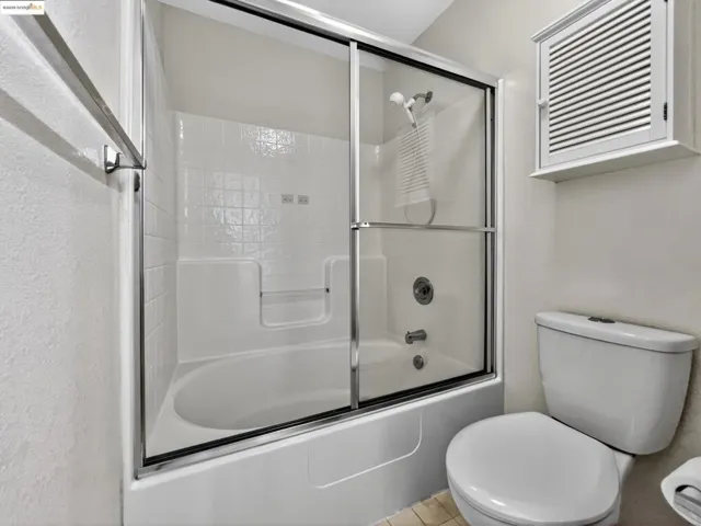 Full bathroom with enclosed tub / shower combo and tile patterned floors