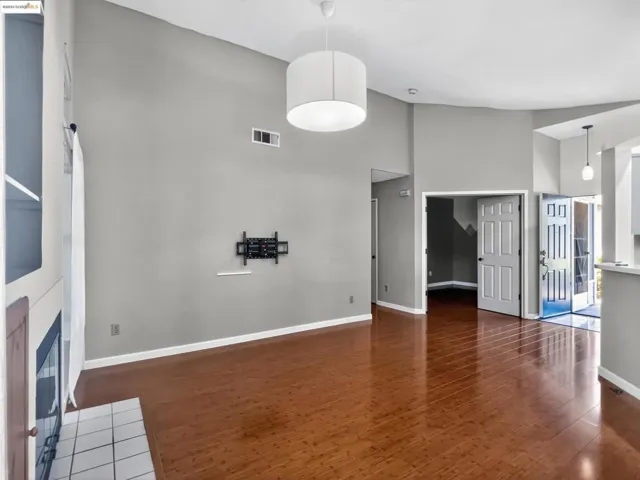 Unfurnished living room with high vaulted ceiling, wood finished floors, and a fireplace with flush hearth