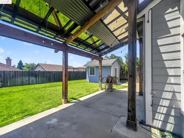 Fenced backyard featuring a patio area and an outbuilding
