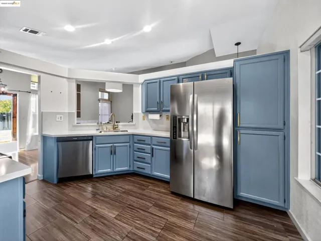 Kitchen with blue cabinetry, appliances with stainless steel finishes, and light countertops