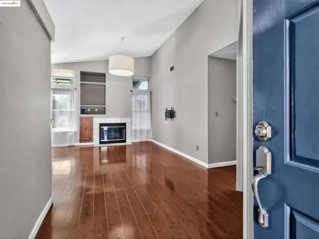 Entryway with lofted ceiling, dark wood-type flooring, plenty of natural light, and a tiled fireplace