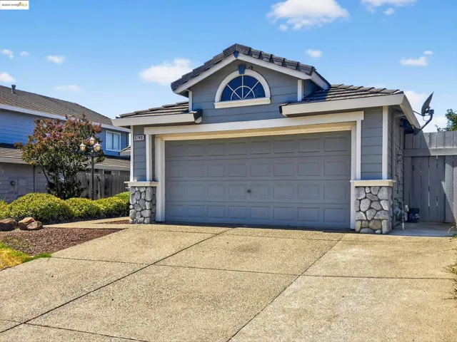View of front facade featuring concrete driveway, a tiled roof, stone siding, and a garage