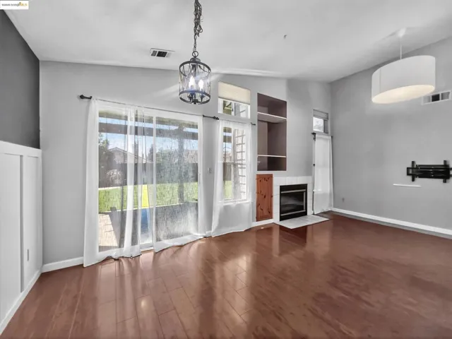 Unfurnished living room with lofted ceiling, wood finished floors, a fireplace, and a chandelier