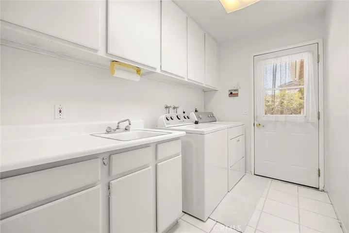 Indoor laundry room with ample cabinets lots of counter space and a dog washing shower