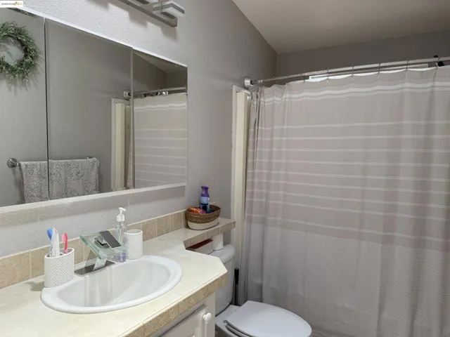 Bathroom with vanity, a textured wall, and a shower with shower curtain