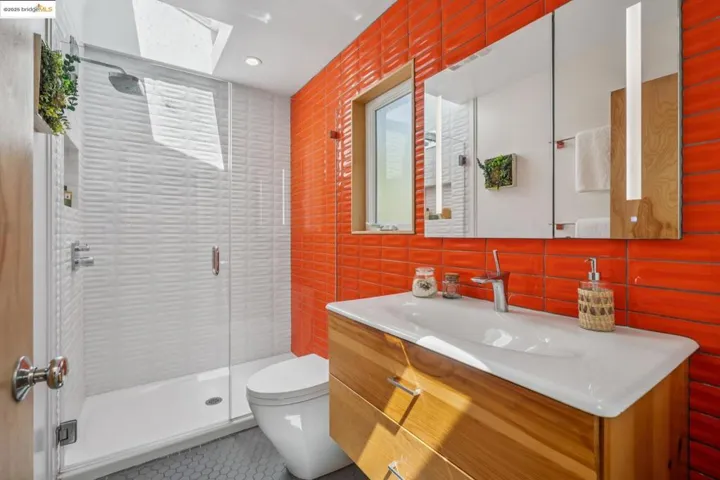 Full bathroom with a skylight, vanity, a stall shower, tile walls, and tile patterned flooring