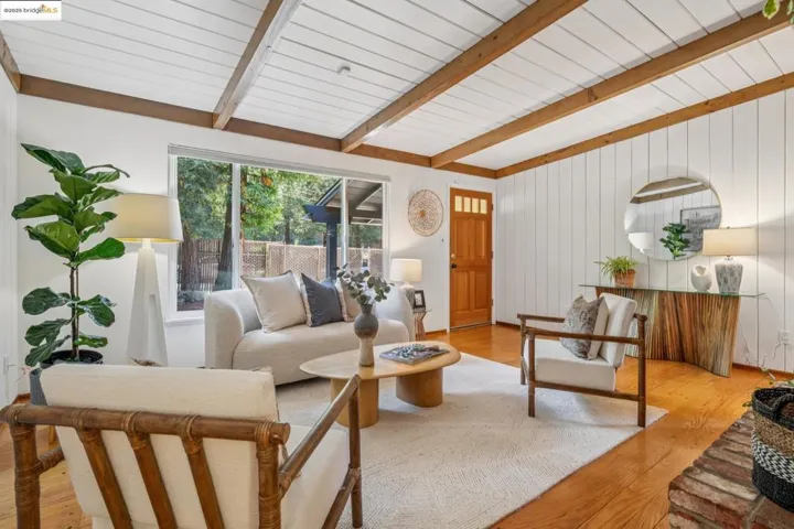 Living area featuring light wood-style floors and a wood ceiling with exposed beams