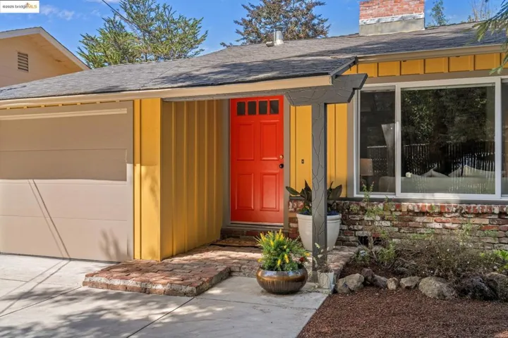 View of exterior entry featuring roof with shingles, a chimney, and board and batten siding