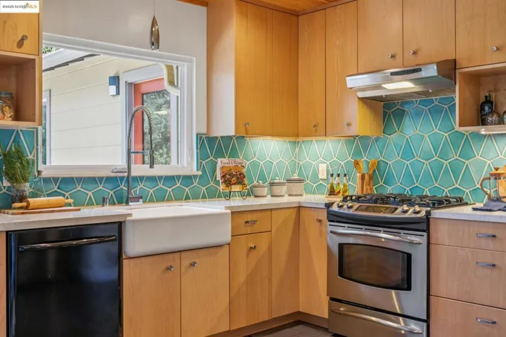 Kitchen with stainless steel gas range, open shelves, dishwasher, under cabinet range hood, and light countertops
