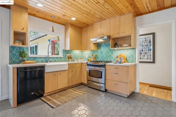 Kitchen with open shelves, wood ceiling, light brown cabinets, stainless steel stove, and light countertops